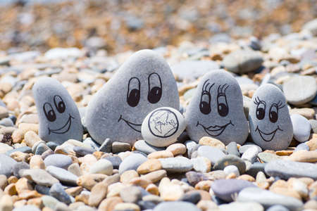 Pebbles with drawn faces in the sand. Father, mother, daughter and son. Family vocation conceptの写真素材