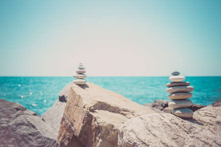 Stones pyramid on sand symbolizing zen, harmony, balance. Ocean at sunset in the background.の写真素材