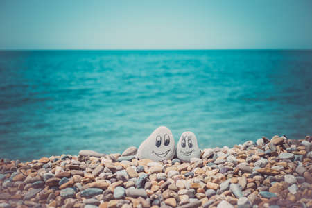 Pebbles with drawn faces in the sand. Loving couple. Travel conceptの写真素材