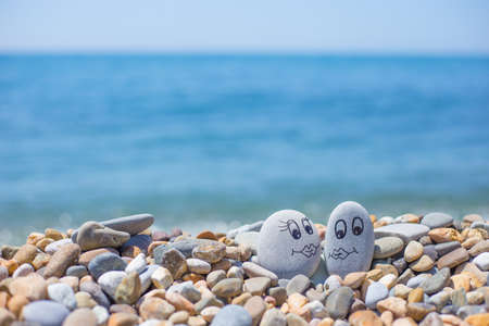 Pebbles with drawn faces in the sand. Loving couple. Travel conceptの写真素材
