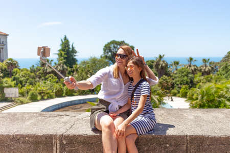 Happy family mother and her adorable little daughter on summer vacation taking selfie with smartphoneの写真素材