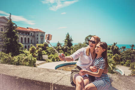 Happy family mother and her adorable little daughter on summer vacation taking selfie with smartphoneの写真素材
