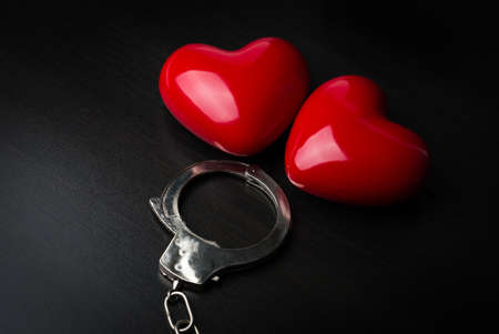 Two red hearts and steel handcuffs on dark background.St Valentine day conceptの写真素材