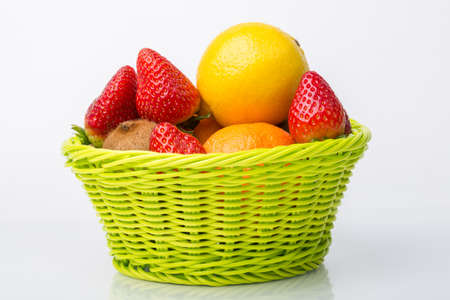 Assorted fruits in wicker basket isolated on whiteの写真素材