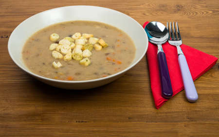 Closeup one bowl of mushroom soup and aromatized bread on dark wooden surfaceの写真素材