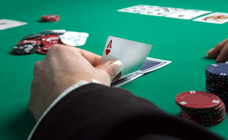 Poker table during a game. Four aces cards holding in hand. Chips and cards on the table.