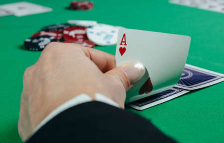 Poker table during a game. Four aces cards holding in hand. Chips and cards on the table.のeditorial素材