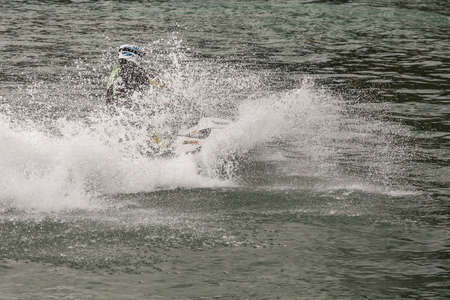 Sistiana, Italy - April 22, 2012: Man on jet ski turns with much splashes