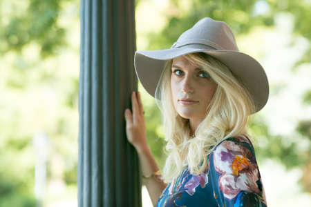 Fashion portrait of happy woman with blue eyes in flower dress. Fashion hat in a sunny day. Girl...