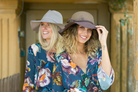 Fashion portrait of two happy woman with blue eyes in flower dress. Fashion hat in a sunny day. Girl with long blonde healthy hair and beautiful smile.の写真素材