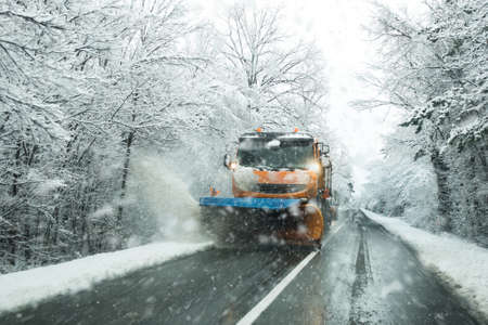 Front view of snowplow service truck and  gritter spreading salt on the road surface to prevent...