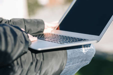Happy smilling handsome redhead young woman sitting on a small wall and working on notebook - Concept Relaxing in nature.の写真素材