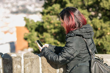 Handsome young woman standing at the street and using her mobile phone