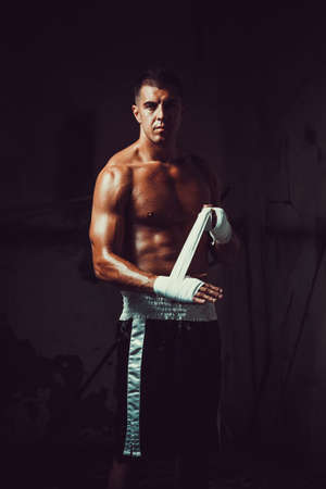 Muscular young man boxer wrapping hand with bandage. Fighter Man concept.の写真素材