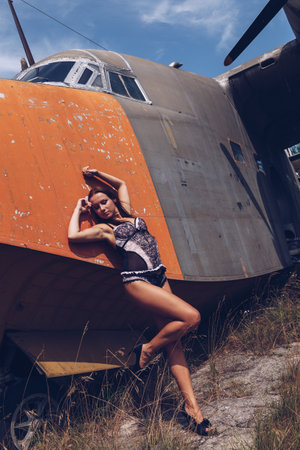 Portrait of a beautiful young girl in sexy  lingerie  near the old abandoned broken plane. Concept...