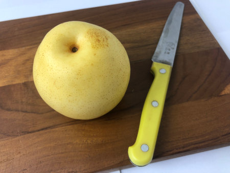 Fresh and organic pears with a knife on a wooden tray.の写真素材