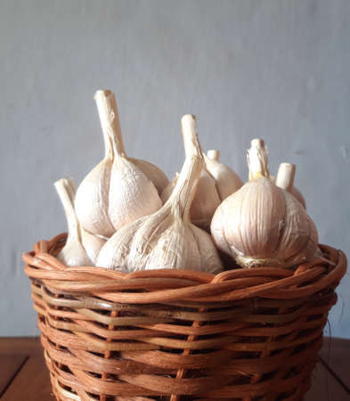 side angle view of many garlic bulb in the wicker basket in wall backgroundの写真素材