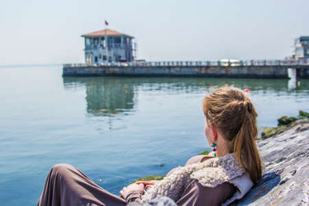 woman sitting on the rocks on the waterfront in Kadikoyの写真素材