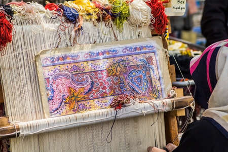 Turkish carpet weaver weaves on a loom on the streets of Istanbulの写真素材