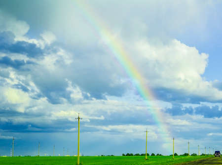 bright rainbow in the stormy sky over the green meadowの写真素材