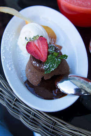 background hot chocolate sweet dessert garnished with strawberries and ice cream on a white plate in cafeの写真素材