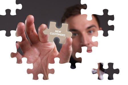 The concept of business, technology, the Internet and the network. A young businessman collects a puzzle with the proper inscription: New customersの写真素材