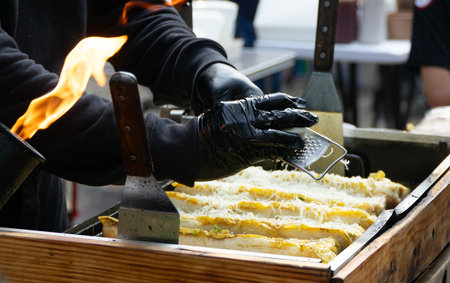 A street food vendor grating cheese with a grater in the street.の写真素材