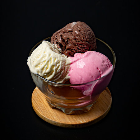 Chocolate, strawberry and vanilla ice cream in one cup on a black backgroundの写真素材