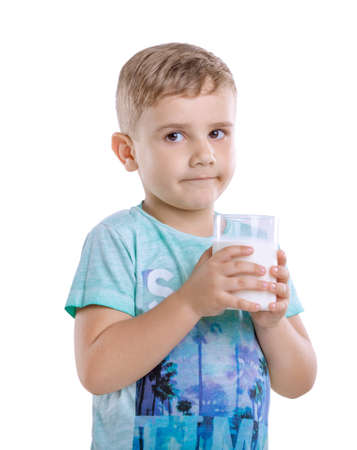 Addorable little boy with fresh and organc milk shake. Portrait of cute toddler boy in blue t-shirt with a glass full of milk. Charming little boy with milk.の写真素材