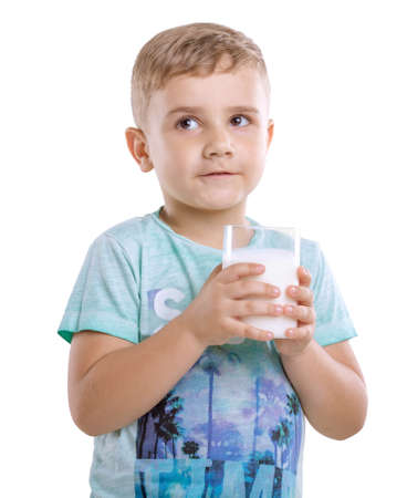 Close-up charming boy with milk. Beautiful little kid with pretty smile is holding a glass of fresh and organic milk isolated on a white background.の写真素材