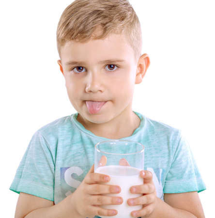 Close-up portrait of a handsome little and blonde boy in blue T-shirt holds organic and fresh milk and shows the tongue, isolated on a white background. Adorable little boy with organic milk.の写真素材