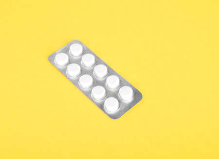 A small package of prescripted medicines on a bright yellow spacious background. Pills, painkillers, drugs, vitamins, tablets in capsules. Pharmaceutical supplement.の写真素材