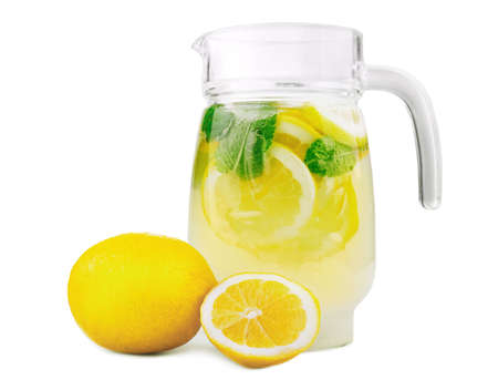 Refreshing and tasty summer beverage with refreshing, juicy and fresh lemons with bright green mint and crushed ice in a modern jug, isolated on white background. Classic lemonade in jug.の写真素材