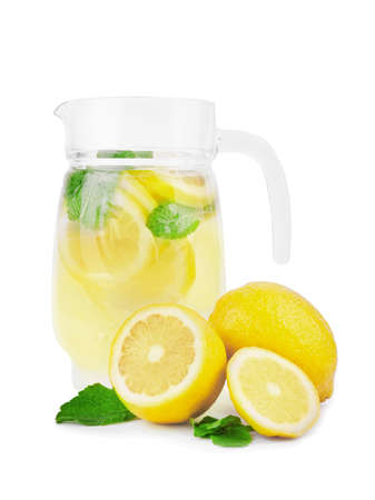 A transparent jug of summer mojito beverages from mineral water, bright yellow lemons, juice limes with tasty leaves of mint, isolated on a white background. Fresh citrus lemonade beverages.の写真素材