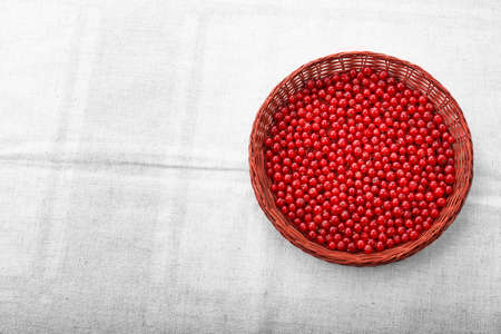 Fresh tasteful red currant in a wooden basket. Delicious vegan breakfast. A light brown basket on a gray piece of cloth. Nutritious fruit ingredient. Colorful red berries.の写真素材