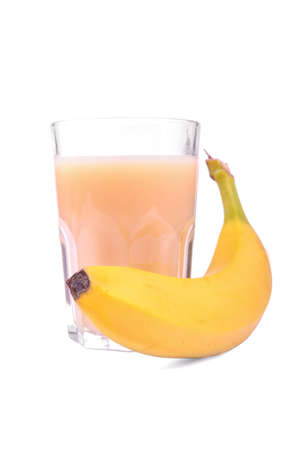 A huge transparent glass full of delicious banana juice or smoothie and next to it a fresh, juicy and ripe bright yellow banana, isolated on a white background. Fresh banana with tasty bananas juice.の写真素材