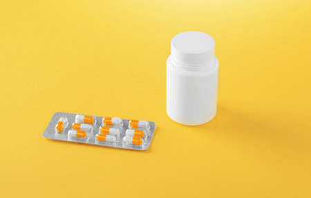 Pharmaceutical medicine pills, tablets and capsules on a yellow background. Pills, tablets,...