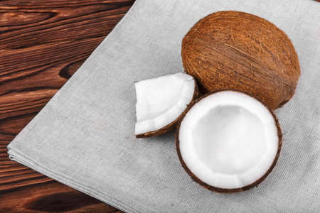 Close-up tasteful coconuts on a dark wooden background. Healthful coconut on a bright gray piece of...