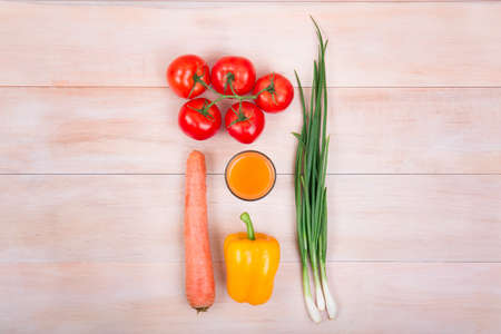 Various vegetables on a wooden bachkground. Nutritious veggies on a wooden table. Perfectly organized tomatoes, carrot, pepper and onion. Healthy vegetarian orange juice.の写真素材