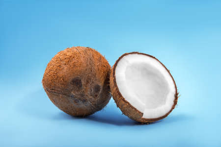 Close-up healthful coconuts on a light blue background. Hawaiian coconut cut in pieces. Organic ingredients for cooking vegan meals. Nutritious exotic nuts.の写真素材