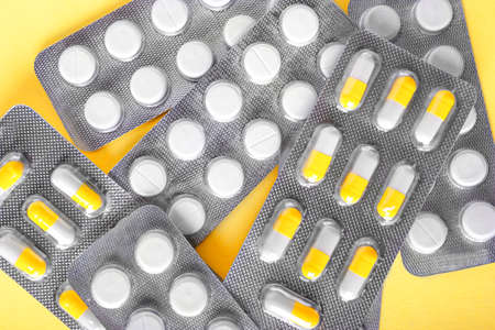 Macro of a few packagings with orange and white tablets on a saturated background. Prescripted organic medication in pills. Medical treatment for recovery from illness.の写真素材
