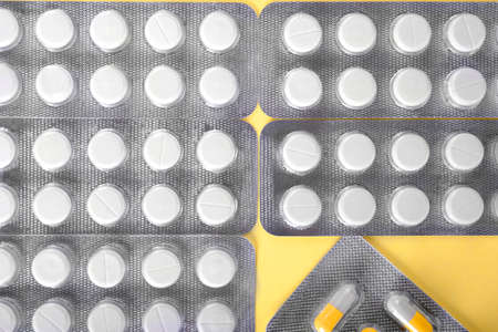 Perfectly organized packages of tablets on a saturated sunny background. Colorful painkillers and antibiotics. Prescripted medication to stop suffering from a disease.の写真素材