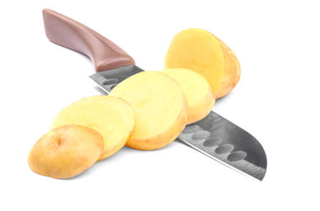 An uncooked peeled potatoes chopped with a sharp gray knife with a brown handle isolated over the white background. Cut potato tubers full of nutritious starch.の写真素材