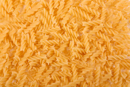 Close-up of the heap of uncooked pasta use as a background. Pasta is a staple food of traditional Italian cuisine. Yellow dry pasta textures background for Italian food ingredient.の写真素材