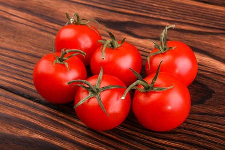 Summer harvest of bright red tomatoes with leaves on a dark brown wooden background. Vegetables full of vitamins. Juicy, ripe and fresh tomatoes. Healthy vegetables.の写真素材
