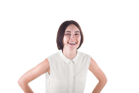 A cheerful and cute young woman with a short haircut and in a white blouse, isolated on a white background. A happy brunette lady with a pretty charming smile. A successful business worker looks happyの写真素材