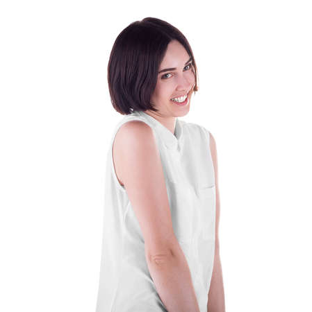 A lovely and cheerfully smiling girl isolated over the white background. A playful young woman posing awkwardly. A gorgeous and successful brunette in a casual white shirt.の写真素材