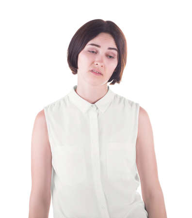 A sad and awkward office lady isolated over the white background. A disgusted young woman in a light and loose casual blouse. A disappointed and unpleased brunette girl.の写真素材