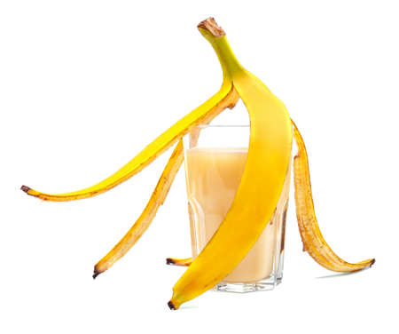 A healthy, juicy, sweet squeezed banana in transparent glass, isolated on a white background. The bright yellow banana peel on top of a large glass. Tropical and sweet fruits.の写真素材