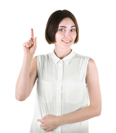 A smiling posing brunette girl isolated over the white background. A professional lady in a bright blouse is pointing up. A cheerful young woman is feeling excited. Happiness and success concept.の写真素材